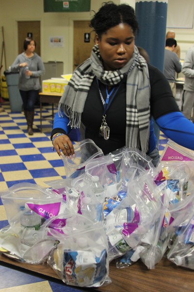 Ms. Reid organizes bags of food for the needy